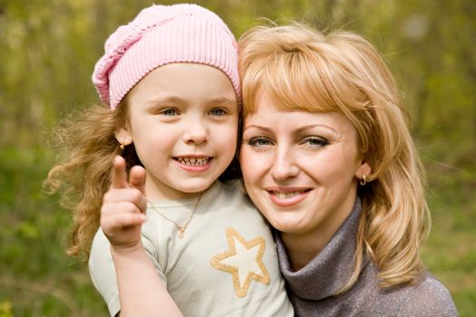 Small blond girl in a pink cap with mum 