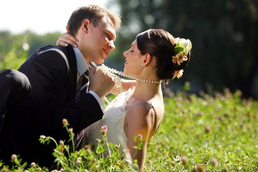 Newlywed couple romancing in field in countryside, groom is pulling new wife towards him.
