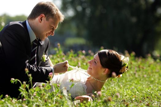 Newlywed couple lying in countryside meadow smiling and romancing.