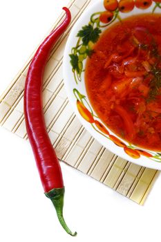 soup in plate and red hot pepper on white background