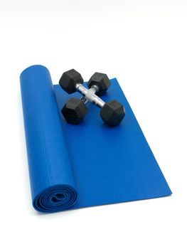 An exercise mat and hand weights isolated against a white background