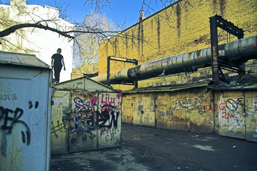 Unidentified boy climbing garage roof and playing in poor area in city outskirts in Saint Petersburg, Russia