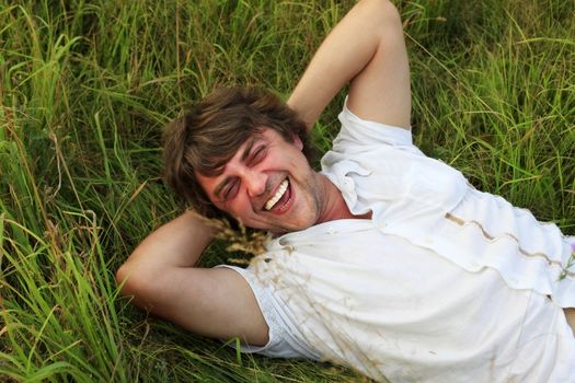 The laughing adult the man weakening in a grass
