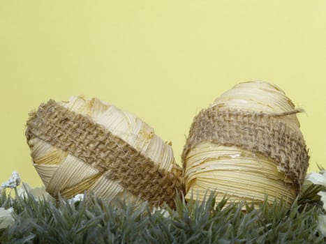 wrapped design on easter egg, artificial grass and blossoms, yellow background