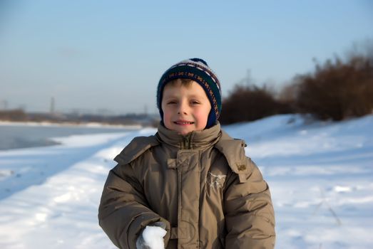 Portrait of the boy walking on coast of the river in the winter