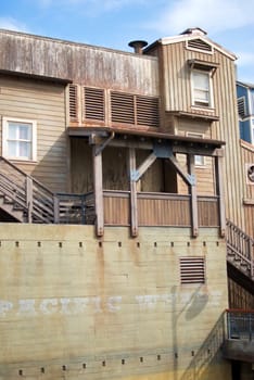 A vertical shot of an old, rundown cannery row building built on a wharf