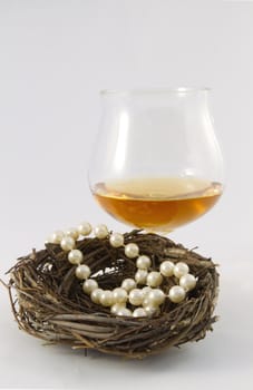 Pearls in a nest egg presentation with a glass of brandy reflect new ways of savings in an unpredictable economy