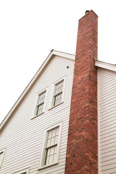 Side of older style white house with tall red brick chimney