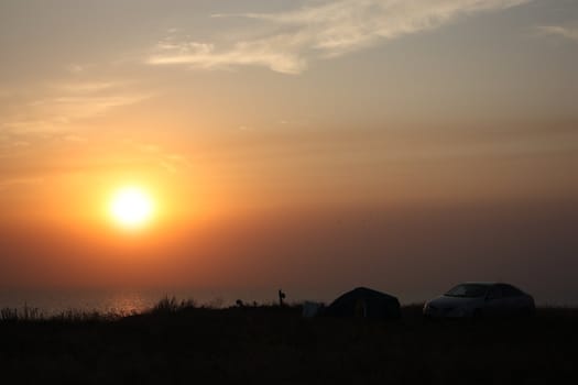 car on the beach at the background of the dawn sun