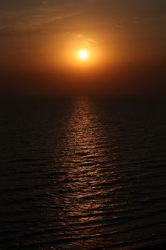 Yellow sun rising over the ocean rippling waves