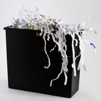 A wastebasket filled with shredded paper.