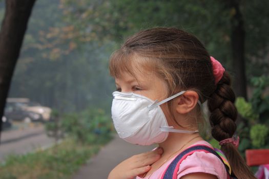 Preschool girl in a breathing mask outdoor 