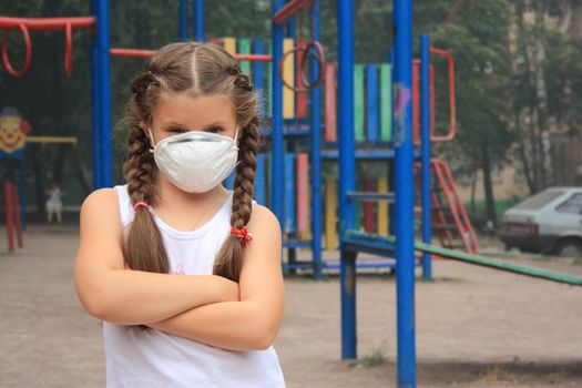 The girl in a breathing mask on a children's playground