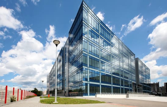 Modern glass building in perspective reflecting cloudy sky