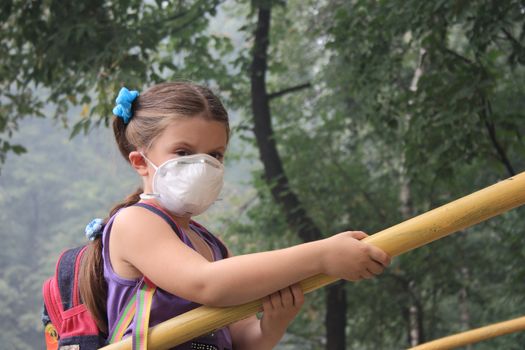 girl in a breathing mask in a smoke-filled backyard