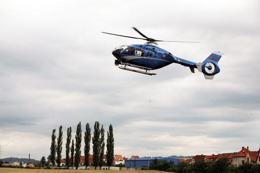 Blue and silver police helicopter flying above