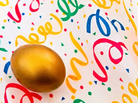Single golden egg in streamer decorated paper