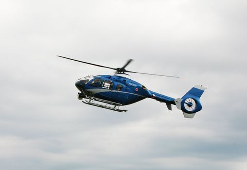 Blue and silver police helicopter flying above