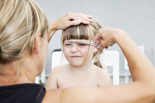 Woman cutting young girls hair