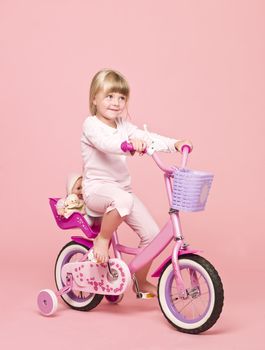 Young girl on her bike towards pink background