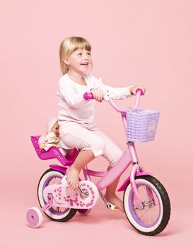 Smiling girl on her bike towards pink background