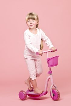 Young girl with a Scooter towards pink background