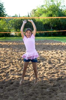 Little girl smiling and jumping at sand volley court