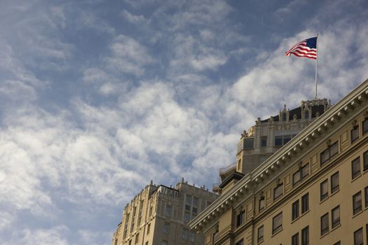 American flag on a building roof against partially cloudy sky