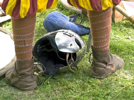 helmet on the green grass between knight legs