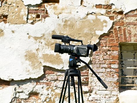 Single working videocamera against the old wall 