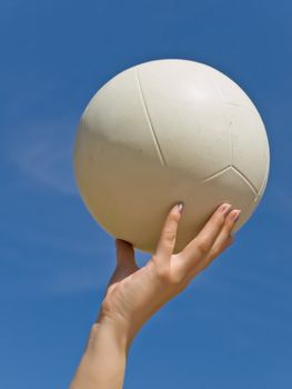 white ball in the woman hand against the blue sky