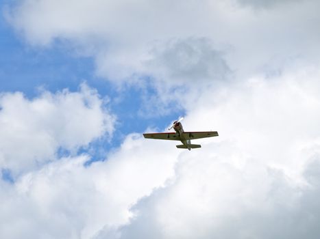 Little aircraft flying through white clouds