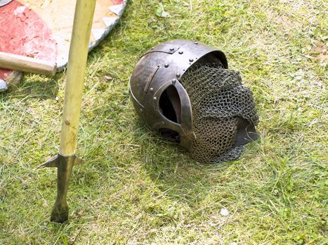 Knight metal helmet, pike and shield at the green grass