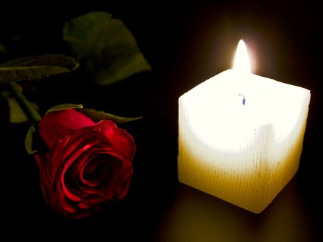 Candle and red rose in the night