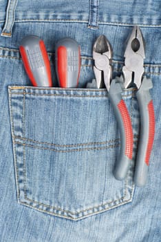 two screwdriver, nippers and pliers in the pocket of jeans