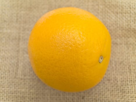 Single orange at the brown linen