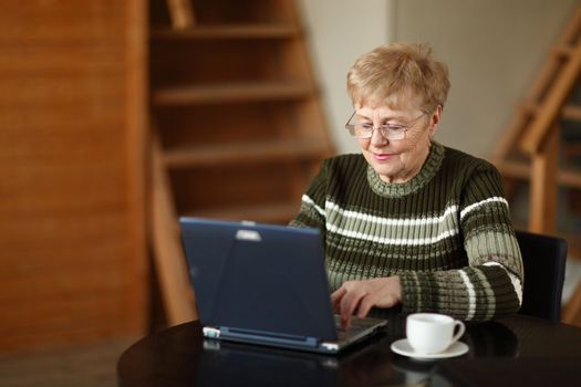 The elderly woman writes  on the computer
