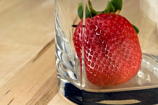 Big fresh strawberry in the whiskey glass on wood table