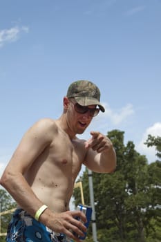 A young man in a swimsuit pointing at the camera