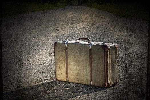 Old suitcase left on a dirt road