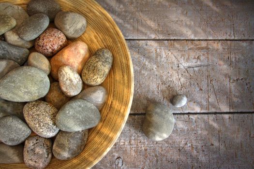 Spa rocks in wooden bowl on rustic wood table