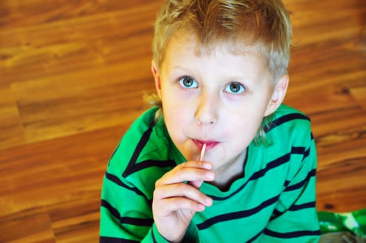 cute little boy with lollipop on the wooden floor