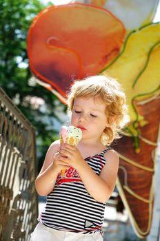 little blonde girl looking with  gladness at the big ice cream