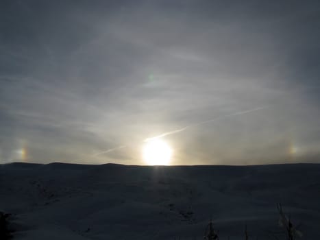 Plateau; a rainbow; the sun; beams; a ridge