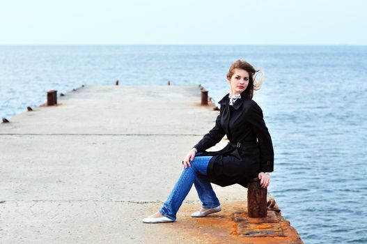 teen girl sitting on the dock in windy weather
