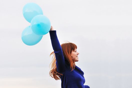 redheaded girl running with balloons over the sky