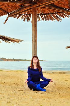 redheaded pretty girl meditating near the sea
