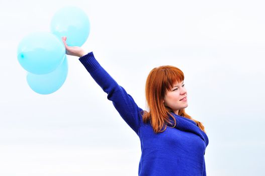 redheaded girl with balloons over the spring sky