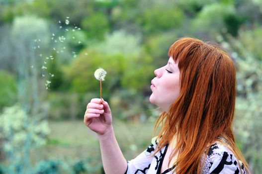 beautiful redheaded teen girl  blowing on dandelion
