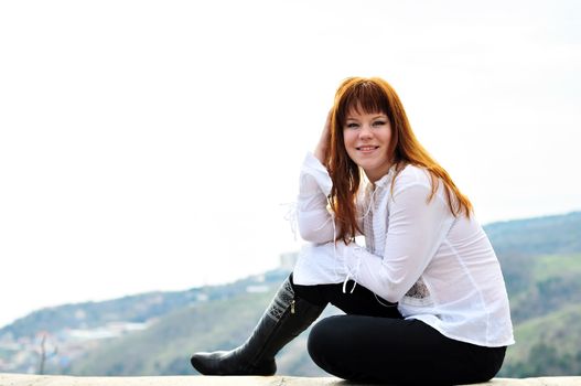 redheaded girl sitting on the  wall 